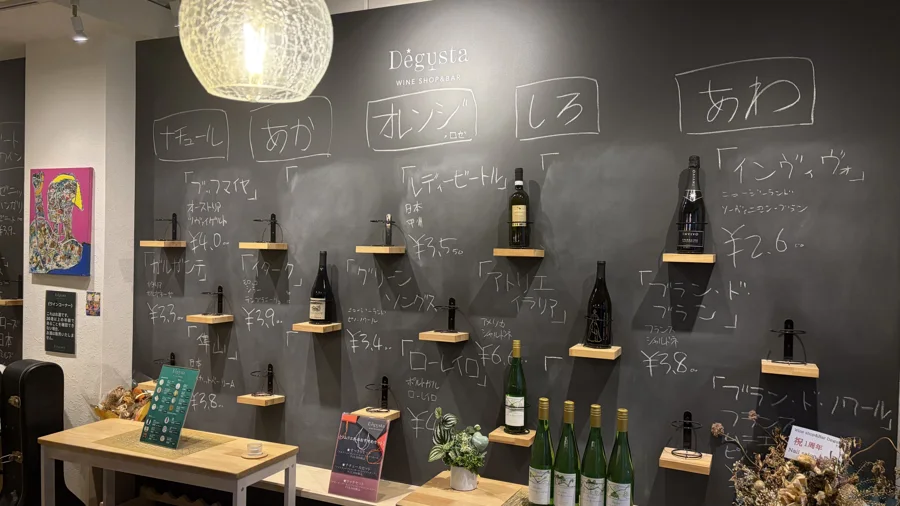 手書きの黒板と棚に並ぶ販売用のワインボトル